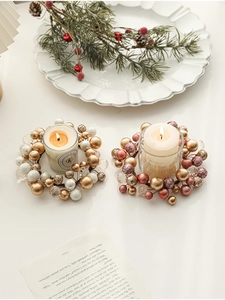 Top view of two glass candle holders with beaded wreaths and white pillar candles