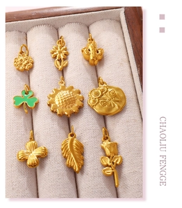 Detailed view of gold flower and clover pendants with green enamel in a jewelry box