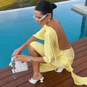 Detail of elegant backless light yellow maxi dress with long sleeves and flowing ribbons
