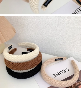 Detail of wide knitted headbands in cream, brown, and black with handmade woven label