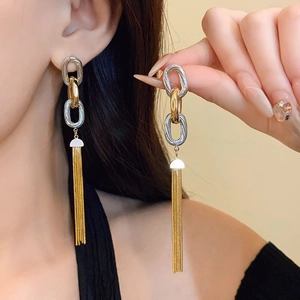 Close-up of long tassel earrings in gold and silver finish on a model's ear