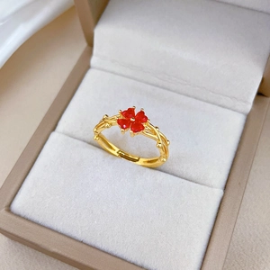 Détail d'une bague trèfle dorée avec pierres cœurs rouges dans son écrin de velours