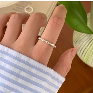 Close-up of minimalist silver twisted chain ring on finger with lifestyle background
