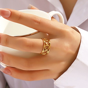 Elegant gold hollow heart open ring in stainless steel worn by model with coffee cup