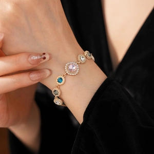 Close-up of a luxury gold bracelet featuring colorful halo-set shimmering crystals on wrist