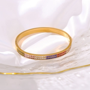 Gold plated stainless steel bracelet with rainbow gemstones on a white silk background