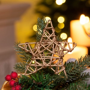 Golden Christmas tree star topper on green branches with warm glowing light bokeh