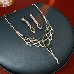Close-up of luxury jewelry set featuring green teardrop gemstones and crystal fringe
