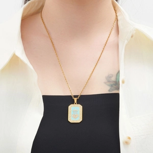 Close-up of golden crown necklace with blue enamel pendant worn on a model