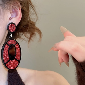 Detail of vintage geometric earrings with red woven texture and amber oval center on model