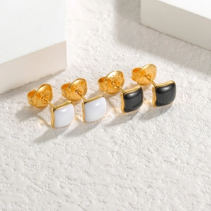 Détail des boucles d'oreilles en acier doré poli avec émail noir et blanc et gravure