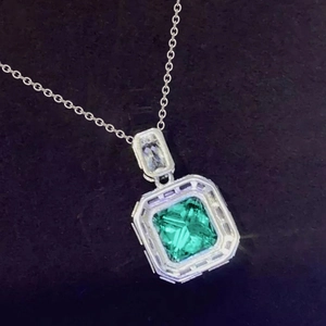 Macro shot of an emerald-cut green gemstone pendant with micro-pave crystals on a silver chain