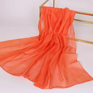 Detail view of smooth orange chiffon scarf draped on a gold stand for a soft texture