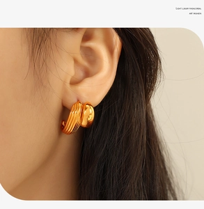 Detail of French style gold heart-shaped C-earrings with vintage textured metal finish