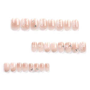 Press-on nails featuring elegant nude gradient with white flowers and silver rhinestones