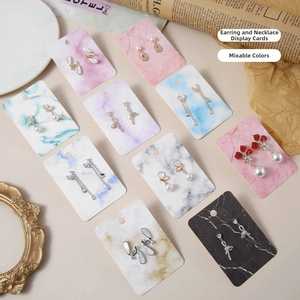 Detail of assorted jewelry set on marble-patterned paper cards with vintage props