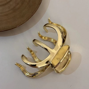 Detailed view of the glossy gold metal hair claw clip highlighting its premium texture