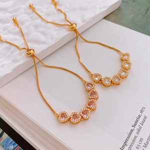 Détail de bracelets réglables plaqués or avec cœurs en zircon rose et blanc brillant