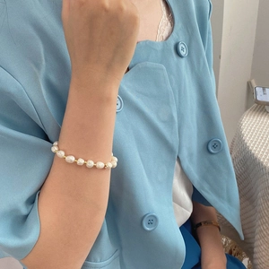 Elegant irregular baroque pearl bracelet with gold beads worn on a female wrist