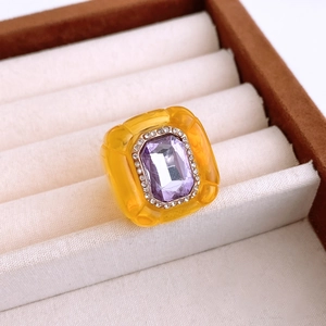 Macro detail of vintage yellow resin ring with purple gemstone and crystals in a jewelry box
