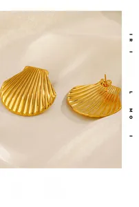 Gros plan de boucles d'oreilles coquillage plaquées or 18 carats sur tissu en soie blanche