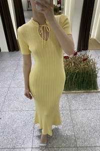 Dettaglio dell'abito in maglia gialla con scollo traforato con lacci e trama a coste
