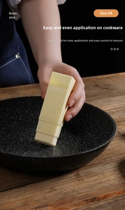 Close-up of yellow butter applicator stick spreading butter on a dark frying pan surface