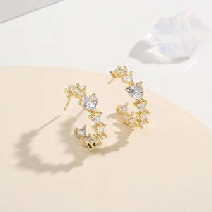 Sparkling gold C-shaped hoop earrings featuring heart-shaped cubic zirconia crystals
