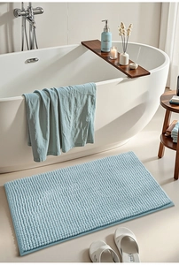 Detailed close-up of light blue chenille bath mat with high-absorbent granular texture