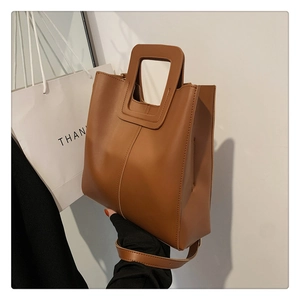 Dettaglio della borsa tote in pelle caramello con manico integrato e trama con cuciture