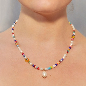 Detail of colorful beads and freshwater pearls necklace with evil eye and droplet charm