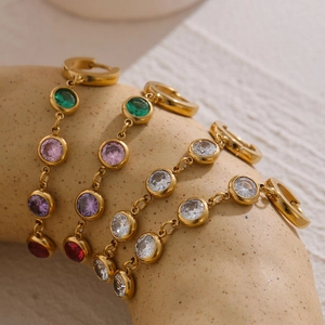 Macro shot of gold tassel earrings with colorful zircons and geometric stainless steel links
