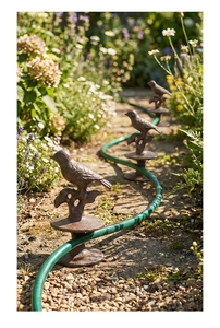 Close-up of vintage cast iron bird hose guide for garden flower bed protection