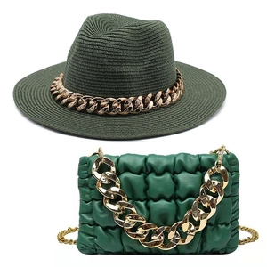 Detail of dark green straw fedora hat and matching quilted cloud bag with gold chains
