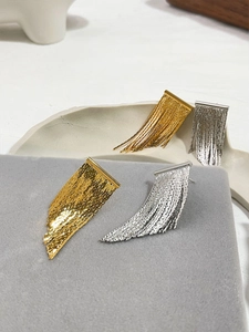 Detail of elegant gold and silver metal tassel earrings on a premium jewelry display