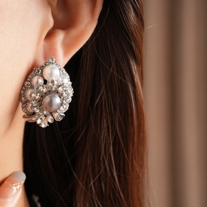 Close-up of vintage flower earrings with pearls and crystals on a model's ear