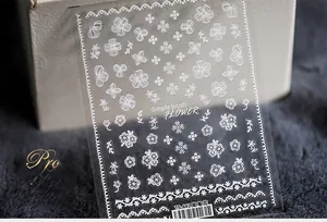 Detail of adhesive nail art stickers with white floral patterns and line art designs