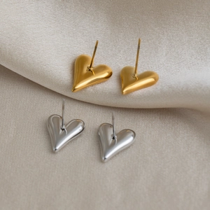 Minimalist 18K gold and silver plated heart stud earrings set on a textured fabric