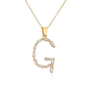 Macro detail of 18K gold plated G letter pendant with baguette cut clear zircons