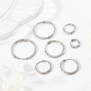Detailed set of six stainless steel hoop earrings with cubic zirconia on marble surface