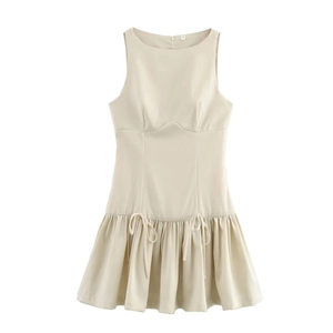 Detail of beige sleeveless dress featuring a pleated skirt and adjustable drawstring bow