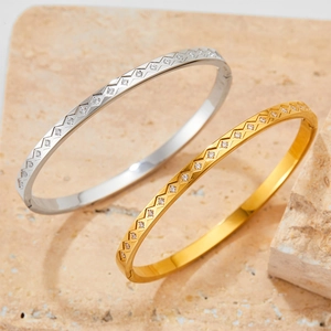 Polished stainless steel bangle with diamond accents on natural stone background