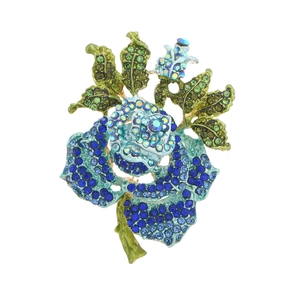 Sparkling vintage blue rose brooch with crystals and green leaves on white background