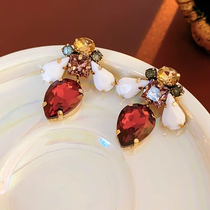 Macro detail of bee earrings with red crystal teardrops and gold finish on a dish
