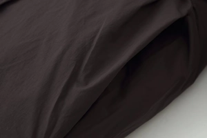 Detailed macro view of dark charcoal water-resistant fabric texture and pocket seam on the coat