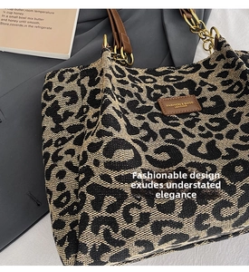 Detail of leopard print tote bag featuring brown leather strap and golden chain link