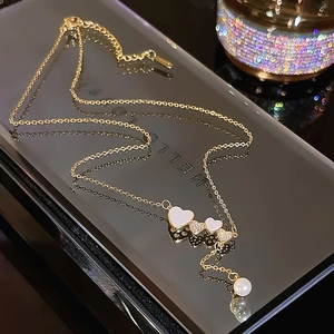 Elegant gold heart necklace with pearl pendant and crystal charms on a black base