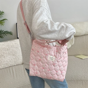 Sac bandoulière matelassé rose avec motifs de lapins et bandoulière réglable sur modèle
