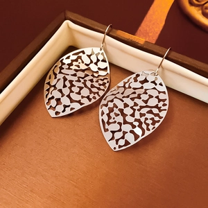 Macro shot of silver hollow leaf drop earrings placed inside a premium jewelry box