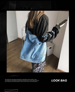 Detailed back view of a oversized light blue washed denim shoulder bag on a model